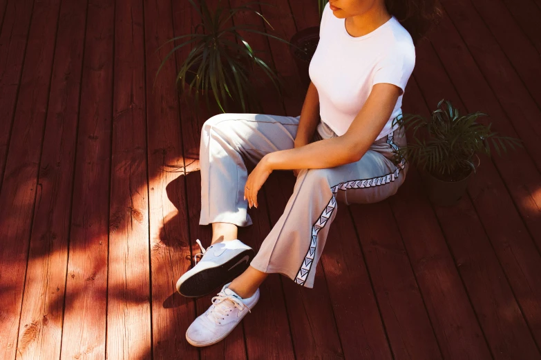 a woman sitting on top of a wooden floor next to a plant