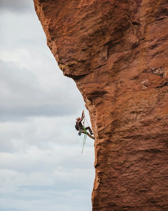 a man is hanging from a rope as he climbs up a rock