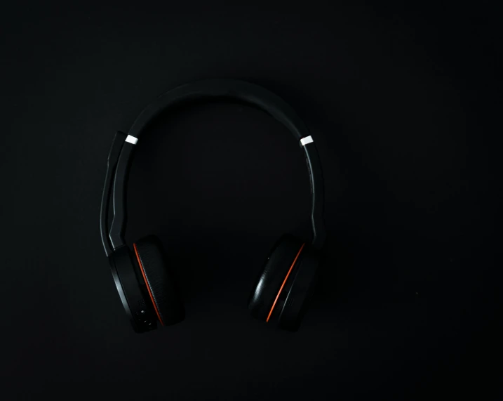 two headphones are laying on a black surface
