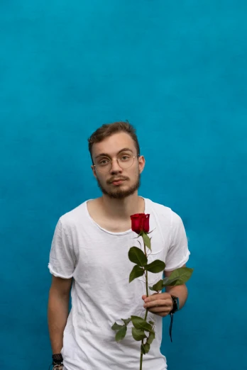 a person wearing glasses holds a flower in front of his face