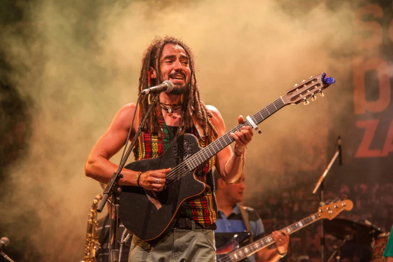 man in bandanna playing guitar while performing at a music festival