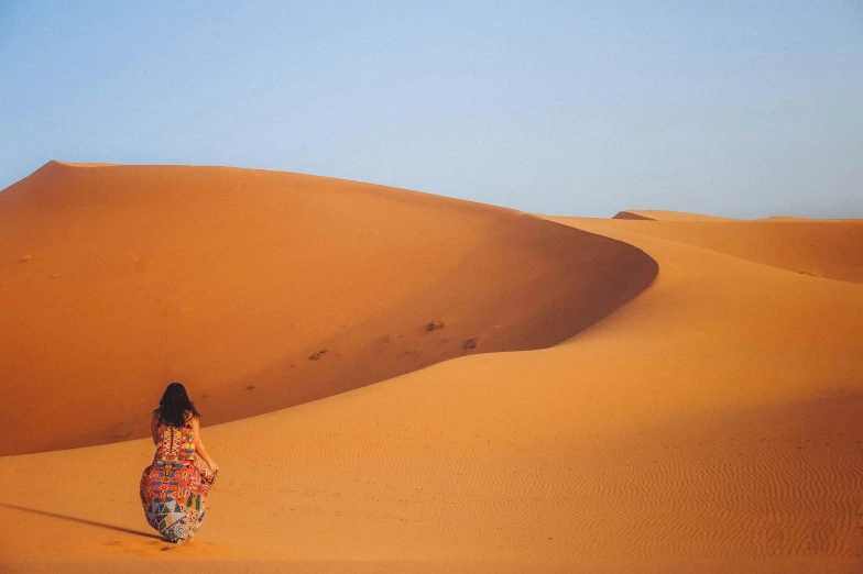 a woman walks through the desert sand