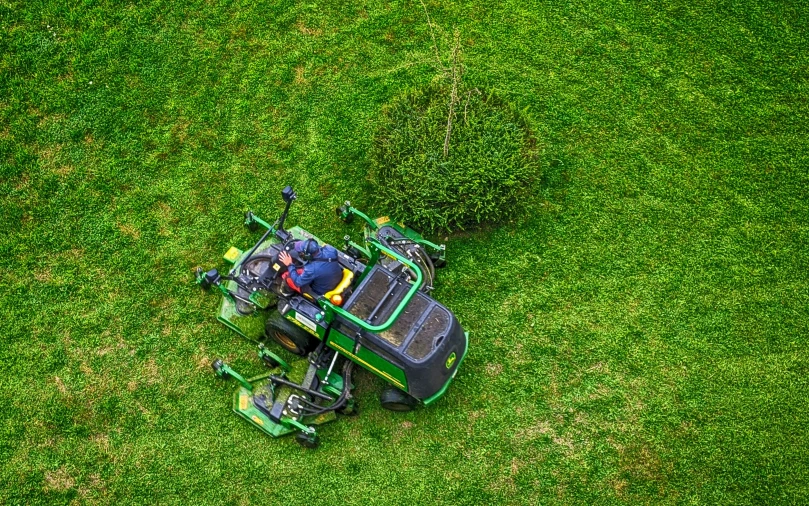 a green lawn with a man mowing the grass