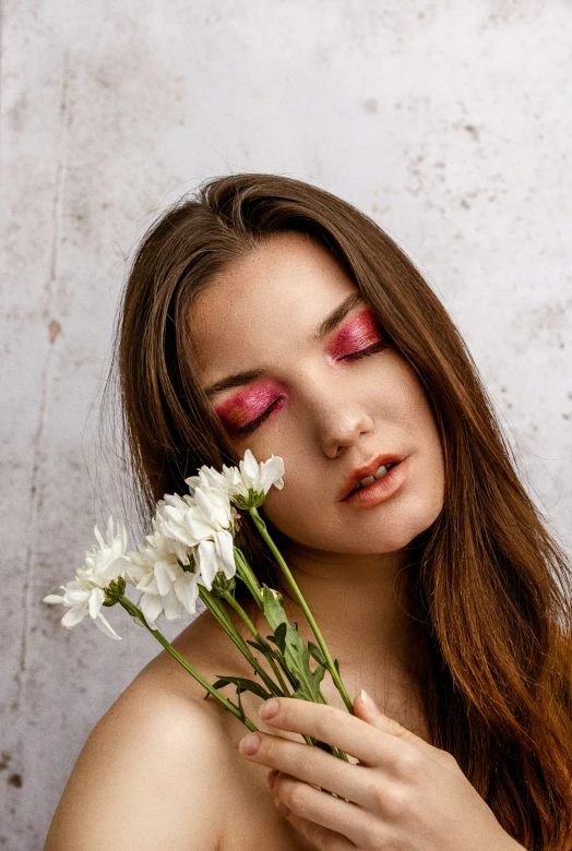 the woman is holding flowers outside by her face