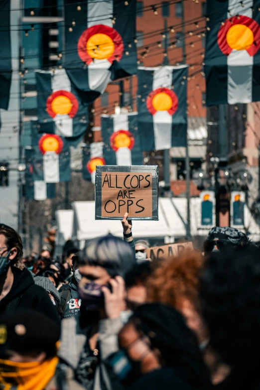 a crowd of people holding up signs and wearing face masks