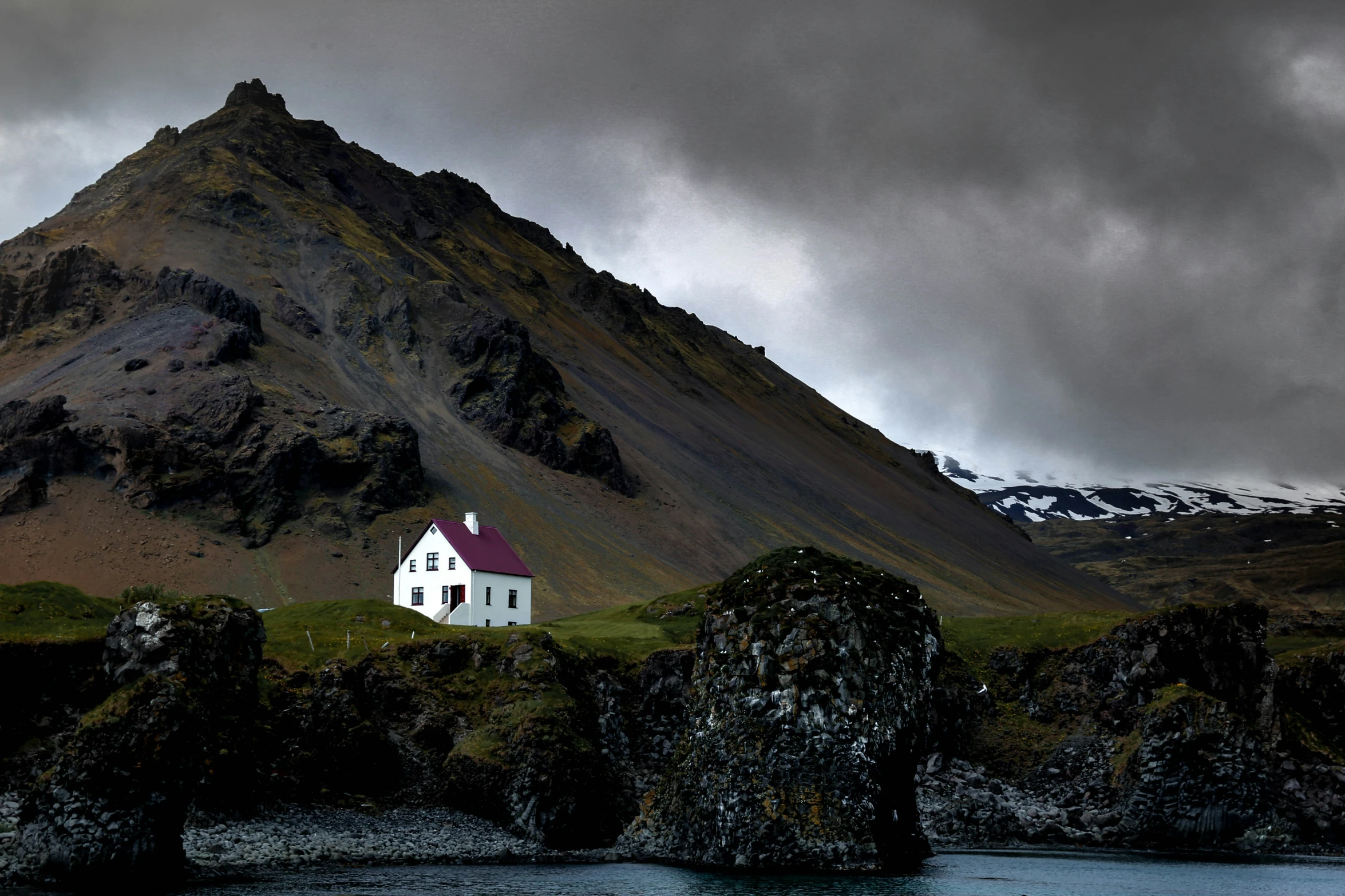 a house on the top of a hill with mountains in the background