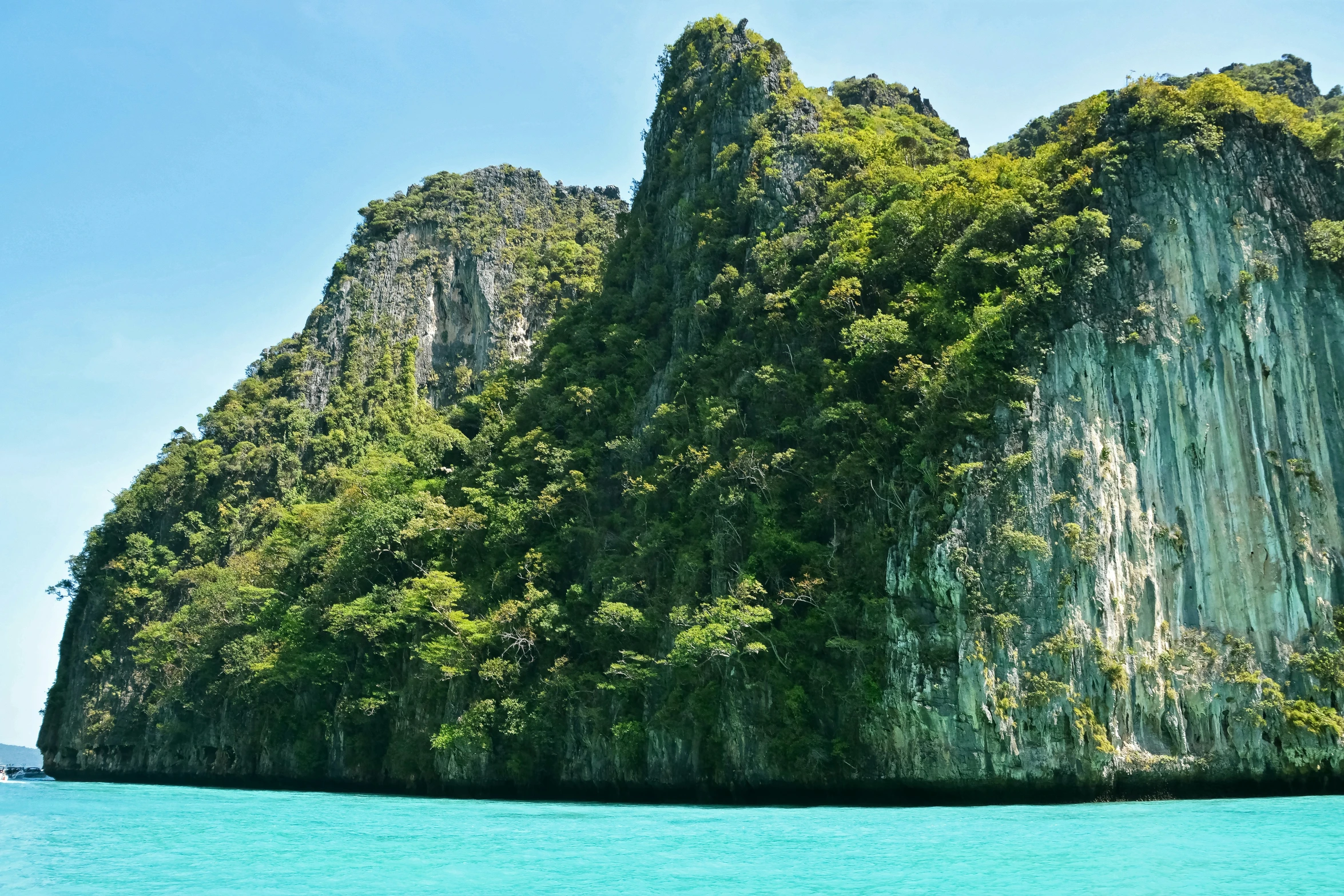 a large rock formation next to an ocean with blue water