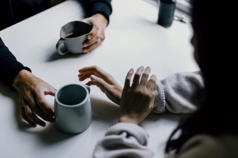 the hands of two people with their hands on the mugs