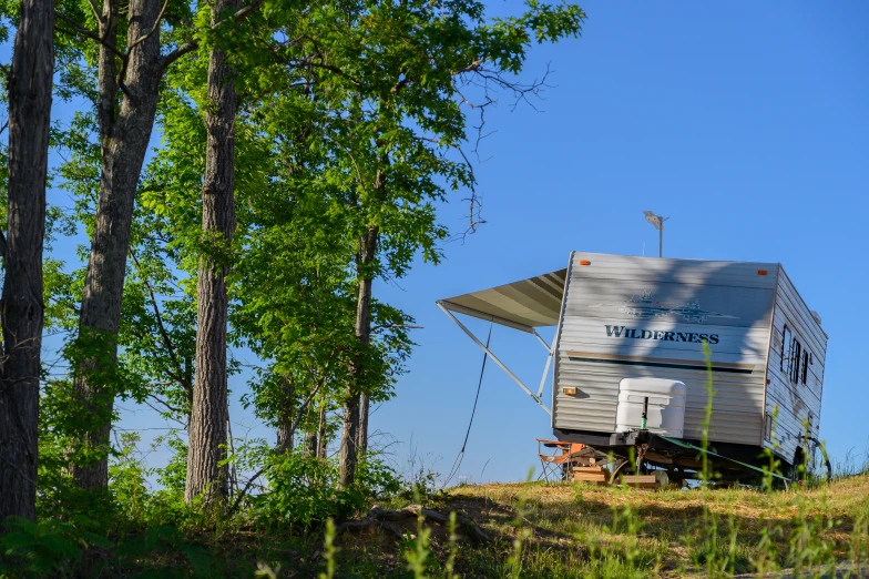 a trailer sitting in a wooded area with a roof