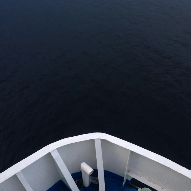 a person standing on the end of a boat in the ocean