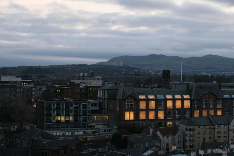 some buildings at night in a city with mountains in the background