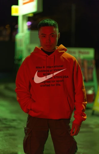 a man in a red nike hoodie is standing outside