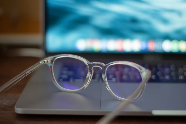 the glasses are sitting on the desk near a laptop