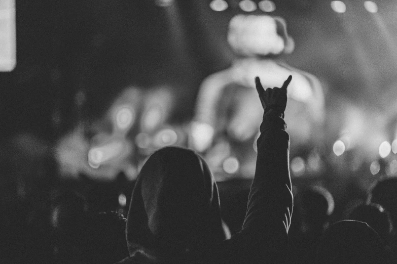 a person raises their hands as they are standing at a concert