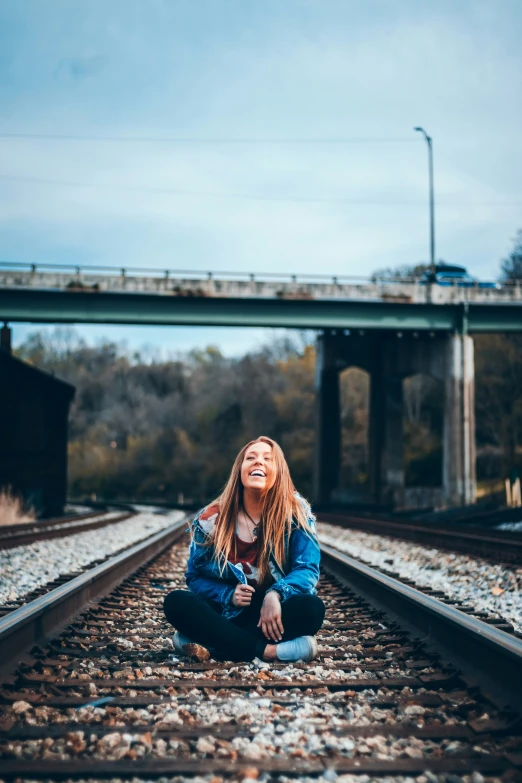 a woman kneeling on train tracks looking up