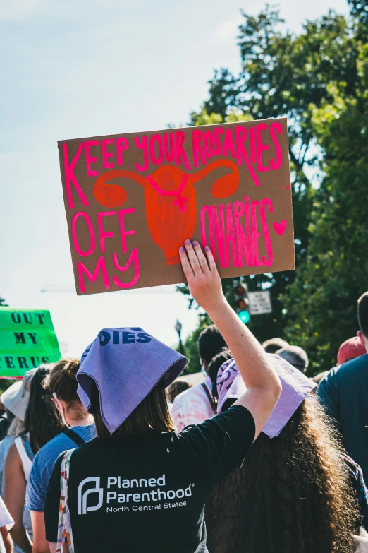 some people holding up a pink sign for a charity