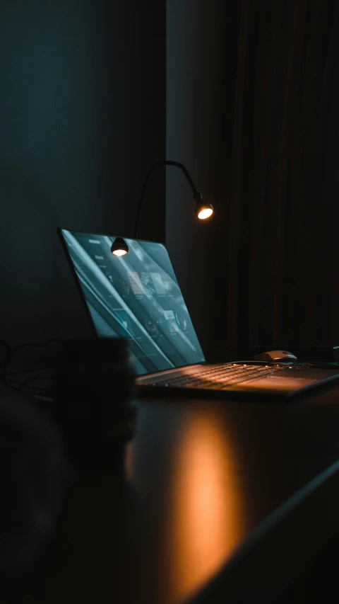 a dark room with a table light shining on a desk