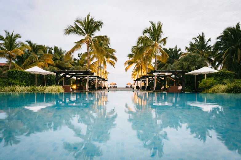 the view from the side of a large swimming pool with lounges and umbrellas