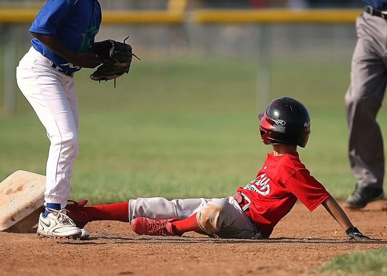 two baseball players on the ground with one playing with the ball