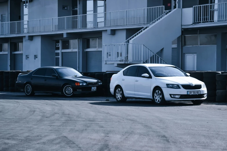 two cars are parked beside each other in front of some apartment buildings