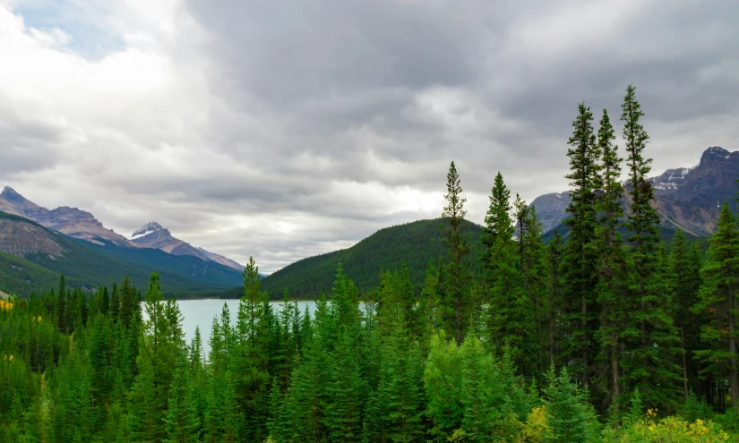 the clouds are gathering over the mountains and lake