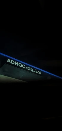 a blue sign that says adnoc club with the word adnoc club underneath it