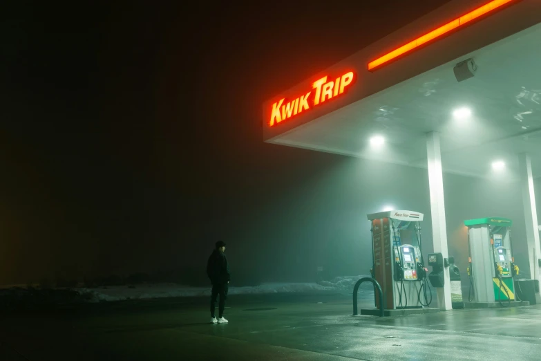 person standing in dark night area next to gas pumps