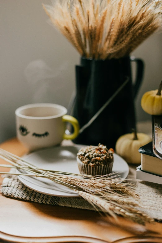 a cupcake is on a white plate next to a black vase