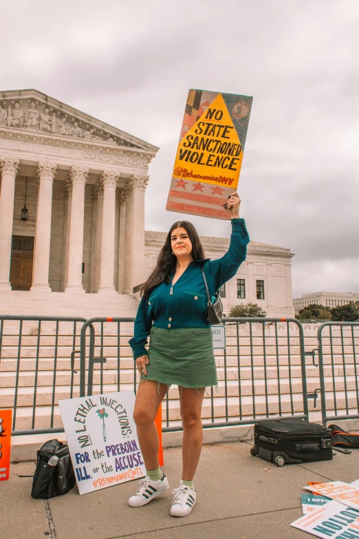 a woman holding up a protest sign in front of the supreme building