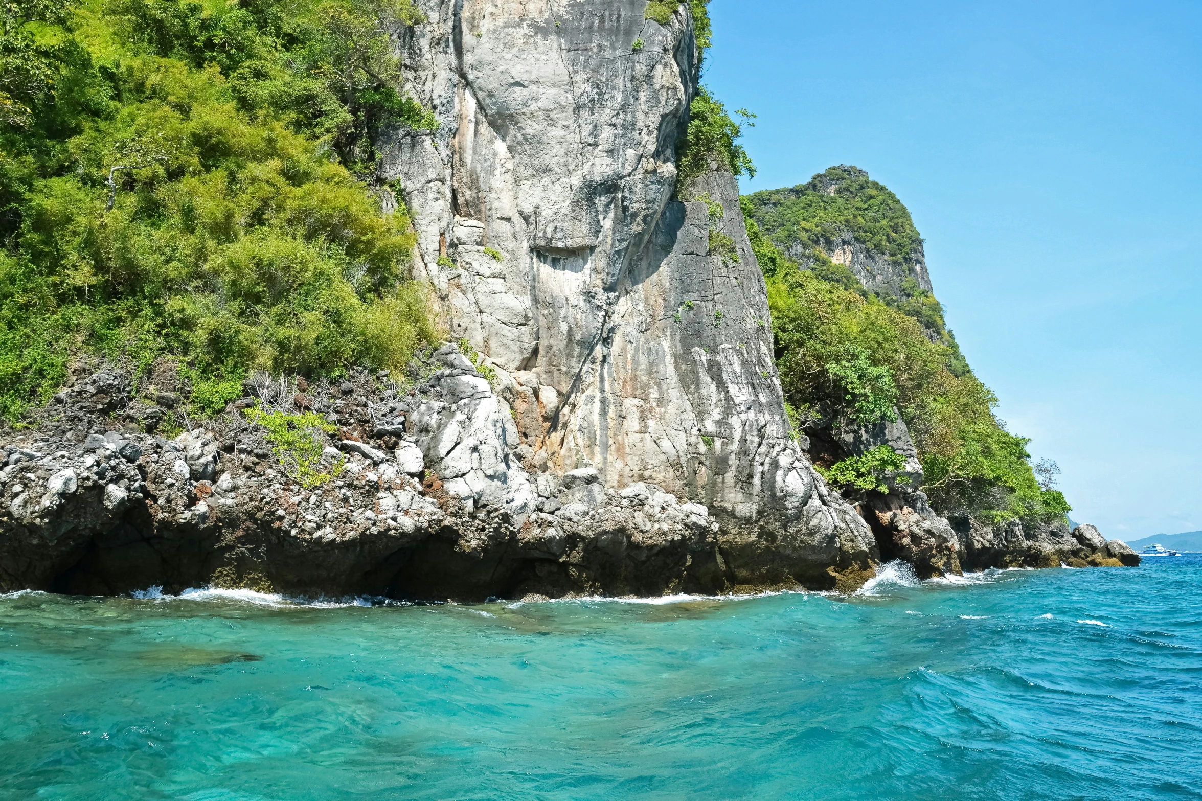 blue water with green rocks on the shoreline