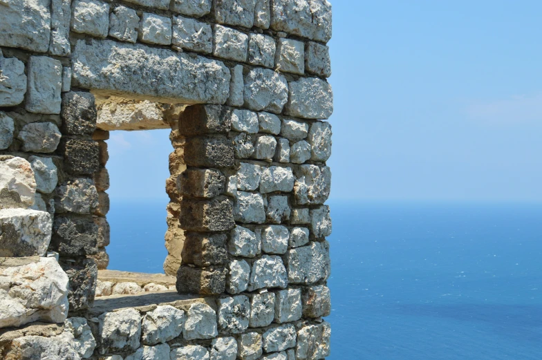 a stone wall with a hole in it by the water