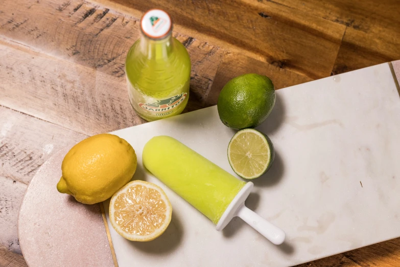 a  board with a juice bottle and limes on it