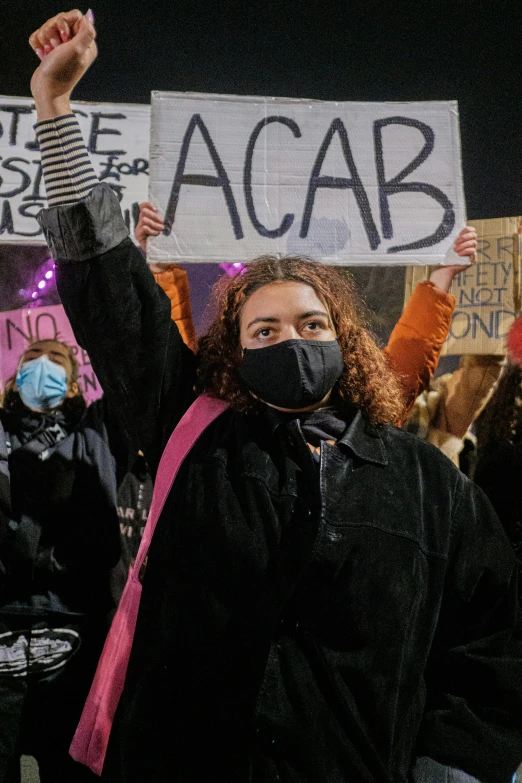 two women hold up placables with the word acab written on them