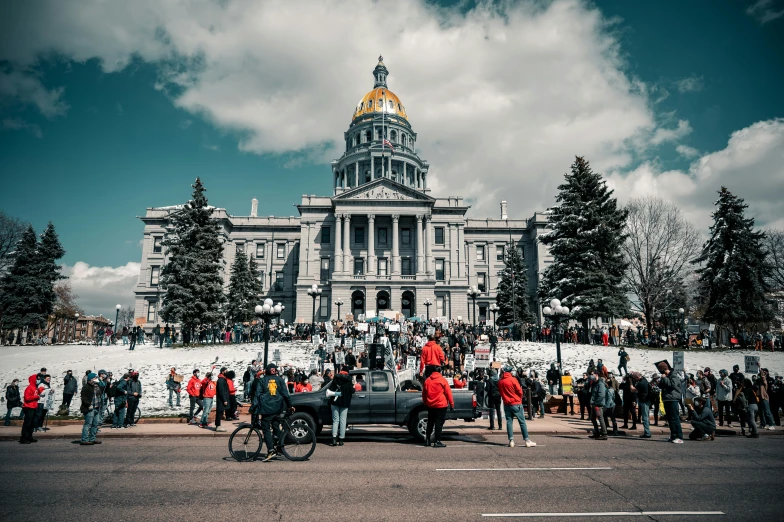 a big crowd stands in front of the state capitol building