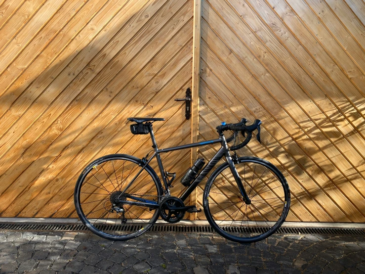 a bike leans against a wood fence in front of it