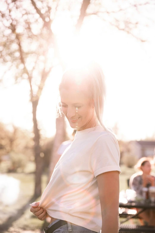 a girl standing next to trees in the sun