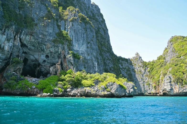 a boat sailing across a blue ocean near rocks