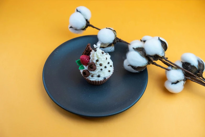 a cupcake on a black plate with cotton balls