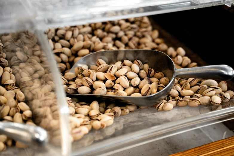 a metal scoop sitting next to some roasted peanuts