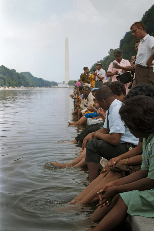 a group of people standing and sitting in water next to the washington monument