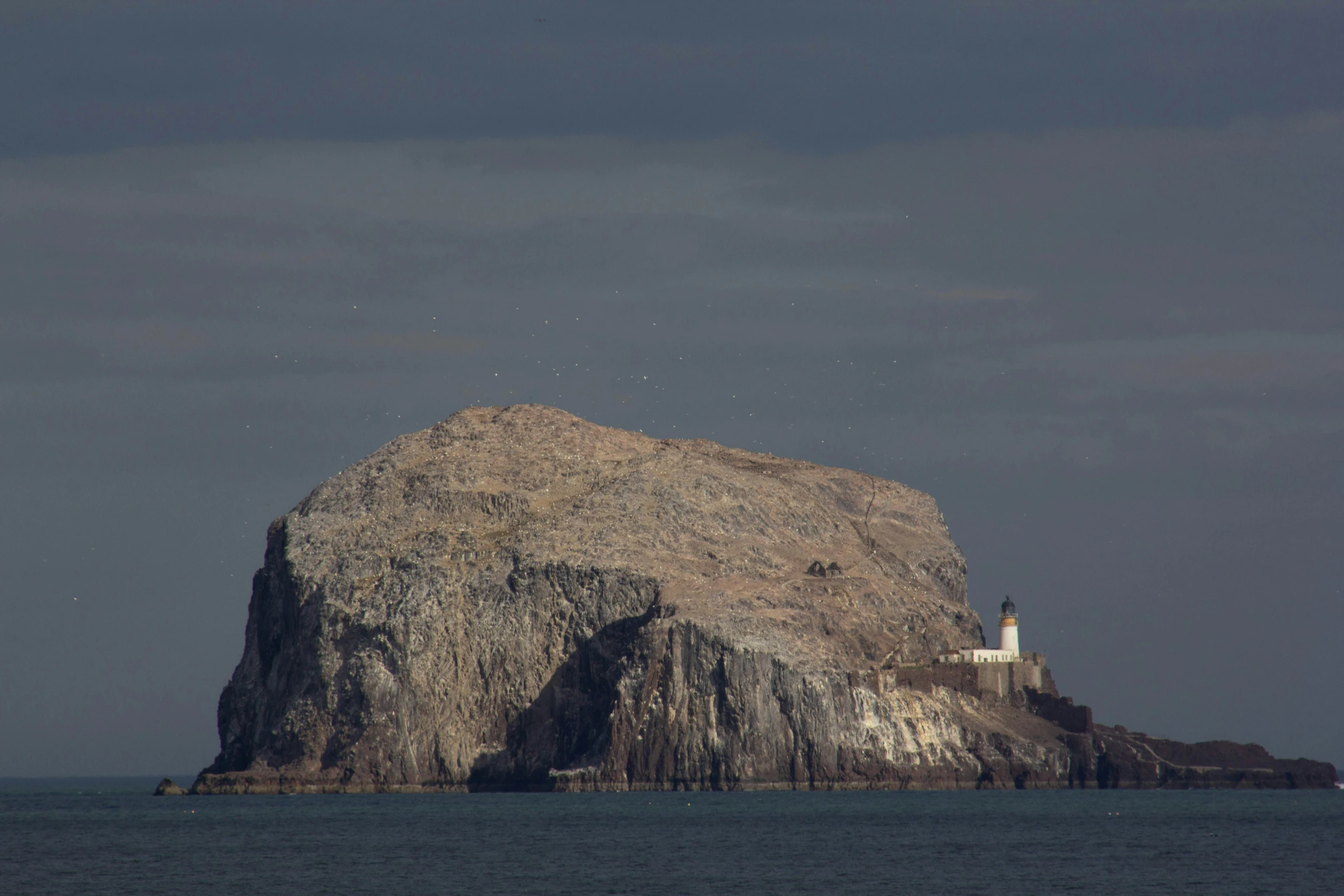 a rock formation on the coast with a lighthouse