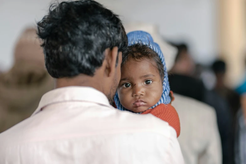 a woman in a blue headscarf holding a small child