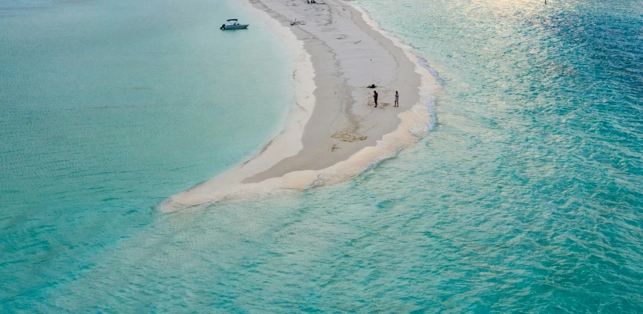 a sandy beach near the ocean with people walking on it