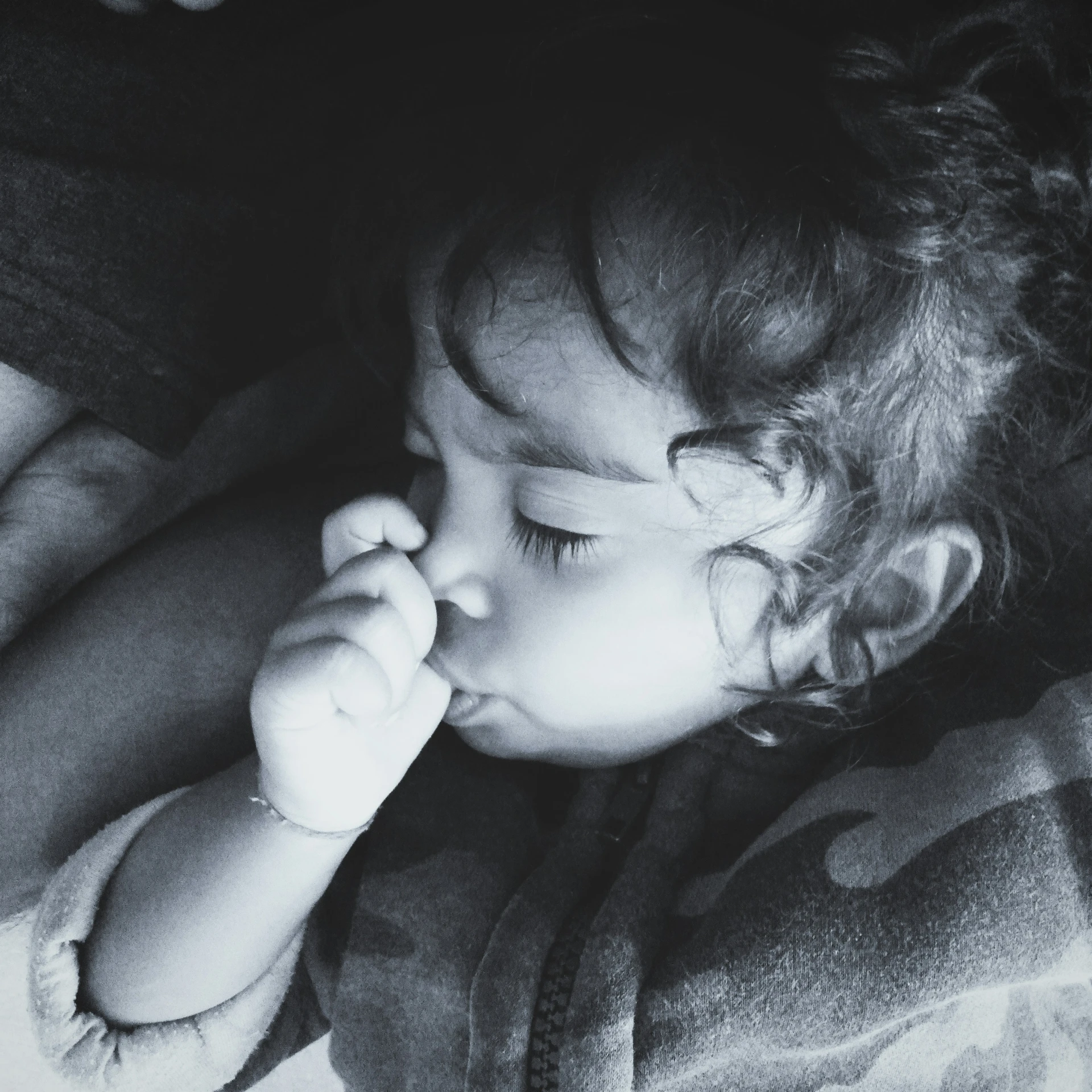 a little girl is laying down with her hands in her mouth
