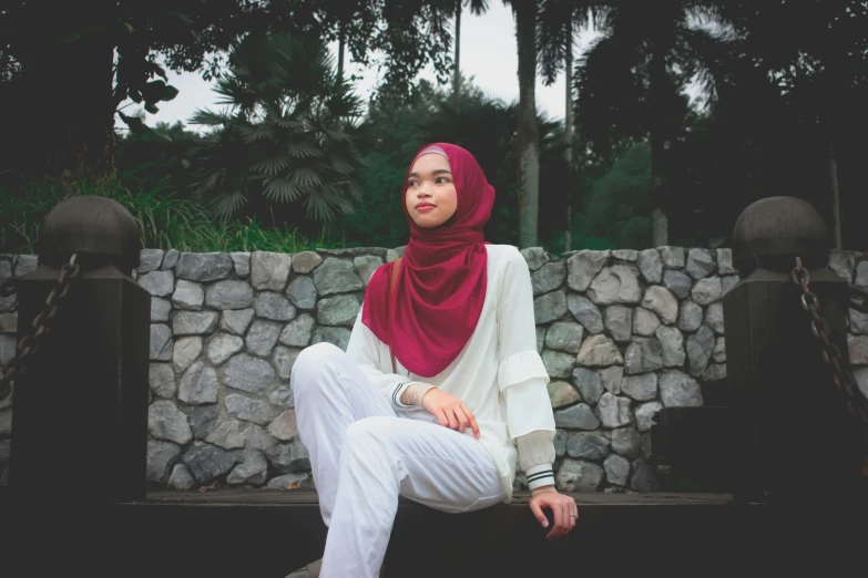 a woman sitting on a stone bench with a scarf dd over her head