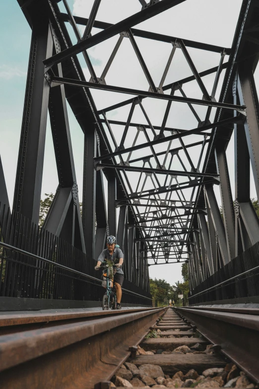 a man on a bike rides along the railroad tracks