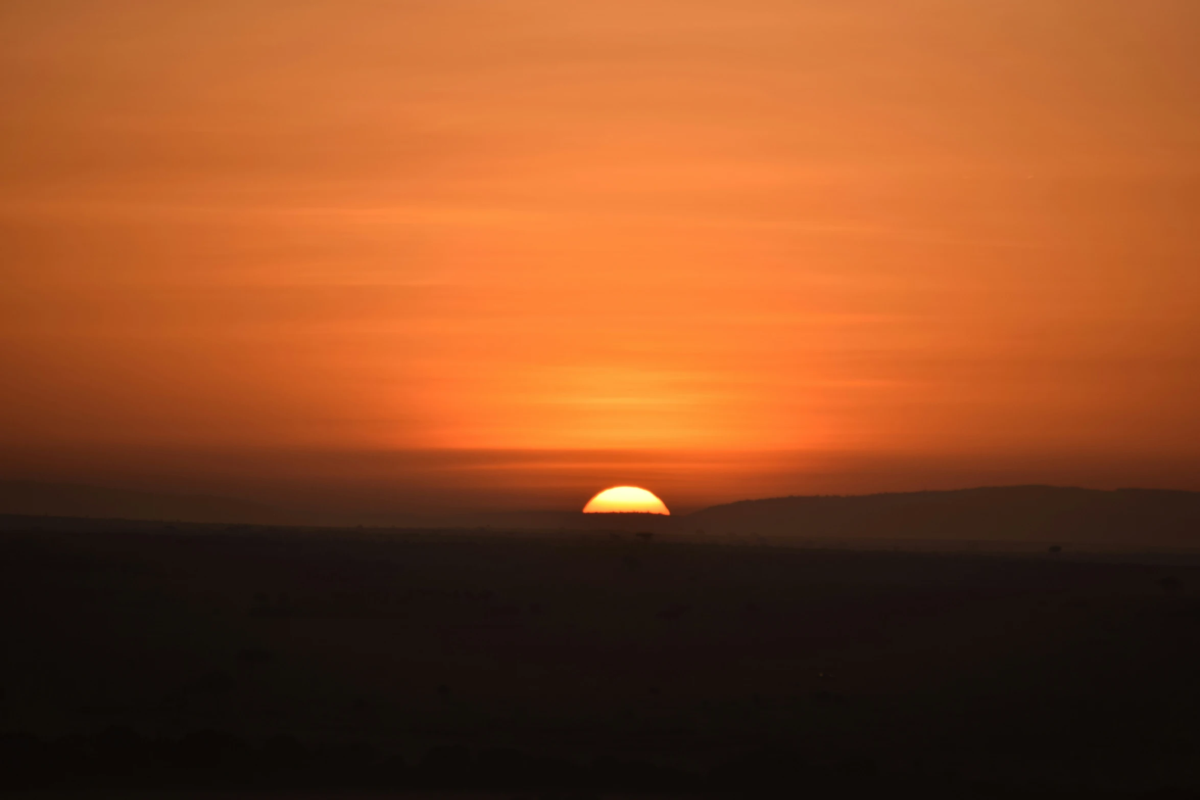 the sun setting with mountains in the distance