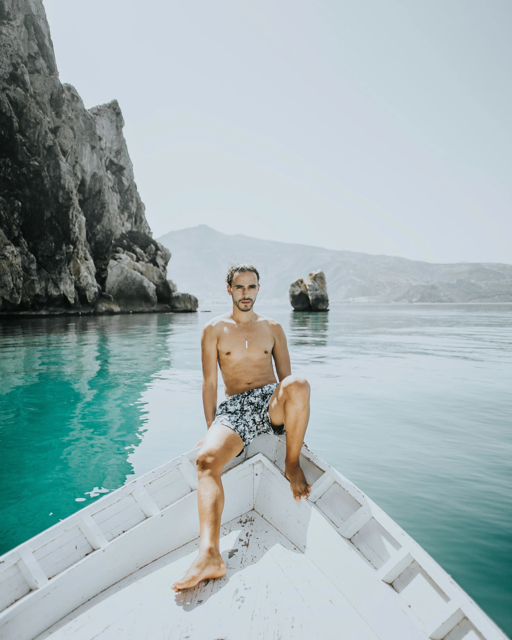 a man with  on sits in a boat in the water