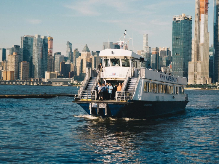 some people boarding on a ferry in front of a large city