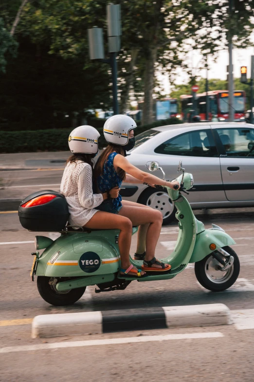 two people on a scooter going down the street